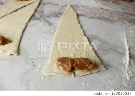 triangle of raw dough with filling boiled condensed milk close-up triangle of raw dough with filling boiled condensed milk close-up 123033537