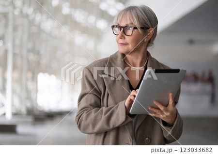 Middle-aged businesswoman using a tablet while standing in a modern office building during a workday 123033682