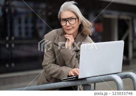 Middle-aged Caucasian businesswoman working outside on a laptop while contemplating her next project 123033746