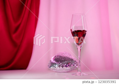 Wine glass with heart confetti and disco on pink background. Minimalist holiday photo for Valentines Wine glass with heart confetti and disco on pink background. Minimalist holiday photo for Valentines 123035391