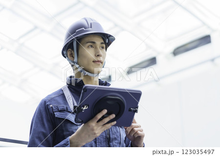 作業服を着てタブレットを持つヘルメットを被った若い男性作業員 撮影協力:スカパー東京メディアセンター 作業服を着てタブレットを持つヘルメットを被った若い男性作業員 撮影協力:スカパー東京メディアセンター 123035497
