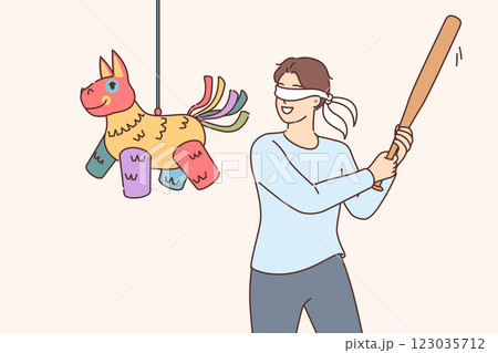 Happy man hitting pinata with baseball bat while trying to get candy at birthday party 123035712