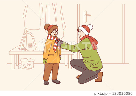 Caring father helps kid put on winter clothes so as not to freeze while walking along cold street Caring father helps kid put on winter clothes so as not to freeze while walking along cold street 123036086