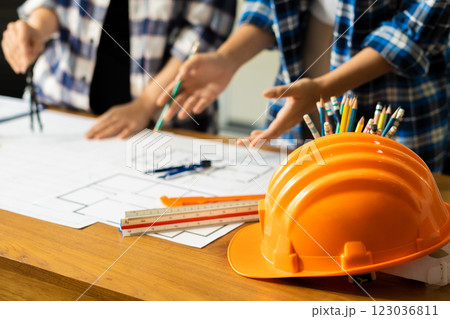 Yellow hard hat on workbench with Construction engineers discussion at construction site. Yellow hard hat on workbench with Construction engineers discussion at construction site. 123036811