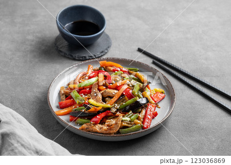 Stir-fry with vegetables and meat on dark background with chopsticks and soy sauce. Stir-fry with vegetables and meat on dark background with chopsticks and soy sauce. 123036869