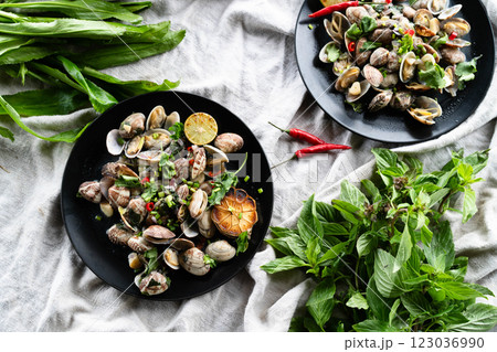 Shellfish dish featuring clams and mussels, seasoned with garlic and surrounded by fresh herbs. 123036990