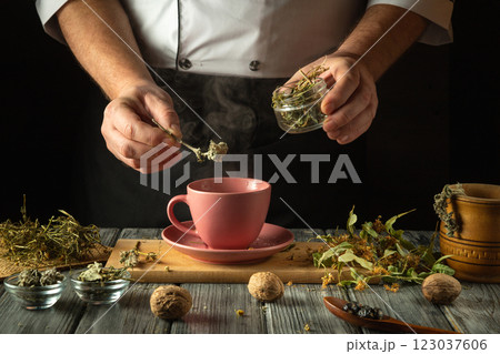Hands skillfully add aromatic herbs to a warming cup, releasing steam as the comforting atmosphere fills the kitchen with earthy scents. Nature's bounty comes alive in this mindful tea preparation Hands skillfully add aromatic herbs to a warming cup, releasing steam as the comforting atmosphere fills the kitchen with earthy scents. Nature's bounty comes alive in this mindful tea preparation 123037606