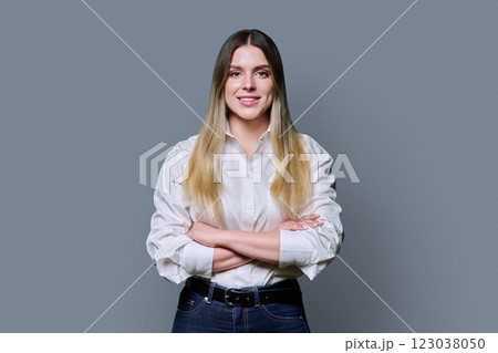 Portrait of young confident smiling woman in white shirt on gray background Portrait of young confident smiling woman in white shirt on gray background 123038050