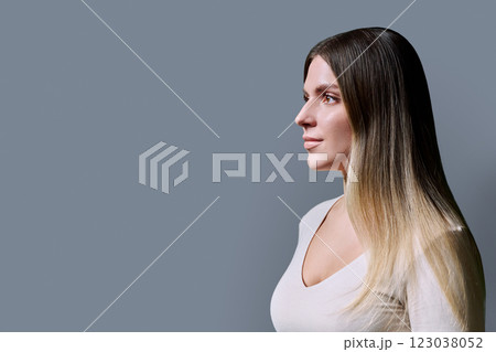 Profile view of beautiful young woman with long hair, gray background Profile view of beautiful young woman with long hair, gray background 123038052