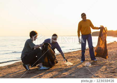 Earth day. Volunteers activists collects garbage cleaning of beach coastal zone. Woman and mans puts plastic trash in garbage bag on ocean shore. Environmental conservation coastal zone cleaning 123038416