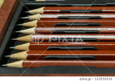 Perspective view of Wooden pencils to each other arranged in a neat row in wooden pencil case on dark background. 123038529