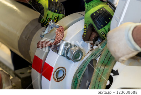 Workers dismantling a flanged pipeline connection using lifting straps and gloves. Workers dismantling a flanged pipeline connection using lifting straps and gloves. 123039688