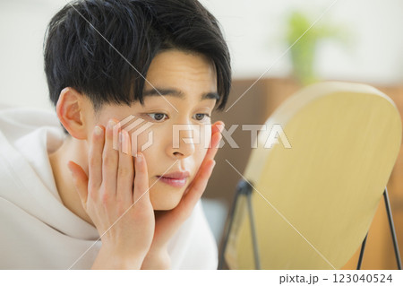リビングで鏡を見る若い男性 リビングで鏡を見る若い男性 123040524