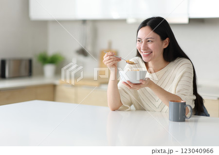 Happy asian woman eating cereals in a kitchen island at home 123040966