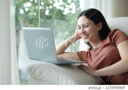 Happy asian woman using laptop sitting at home 123040969
