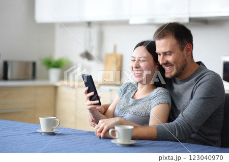 Happy interracial couple laughing checking smart phone Happy interracial couple laughing checking smart phone 123040970