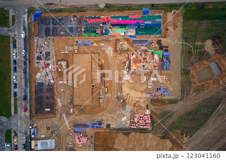 Aerial view of construction site with cranes, foundations and building materials. Residential building under construction. Progress of new development in small town 123041160