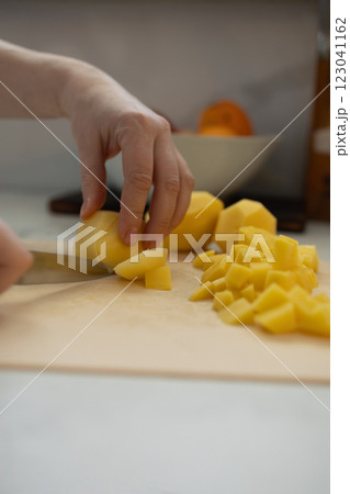 Carefully chop fresh potatoes in a bright and modern kitchen today 123041162