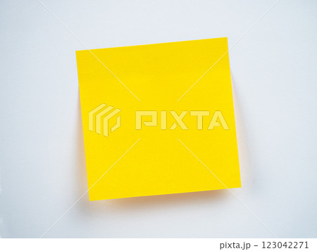 A bright yellow sticky note is placed on a clean white surface, ready for notes 123042271