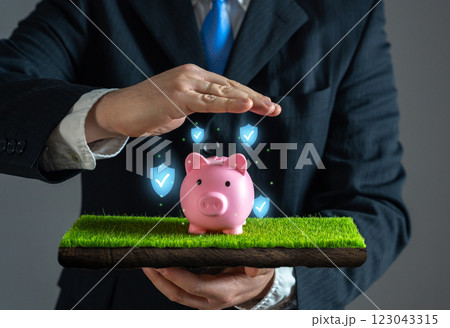 Businessman protects piggy bank with his hand. Concept of saving and guarantee of investments. Safeguarding funds. Financial stability. Protecting assets from risks. Financial security 123043315