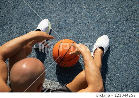 Basketball player relaxing and sitting after game. Outdoor training. View from above. Summer. Close up. Copy space. Basketball player relaxing and sitting after game. Outdoor training. View from above. Summer. Close up. Copy space. 123044258