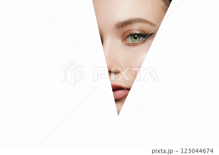 girl with beautiful bright green eyes with shining shadows, looks into the hole of white paper girl with beautiful bright green eyes with shining shadows, looks into the hole of white paper 123044674