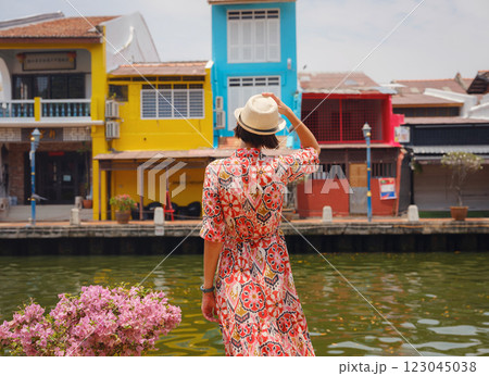 woman in dress and hat exploring vibrant streets of Malacca, Malaysia. 123045038