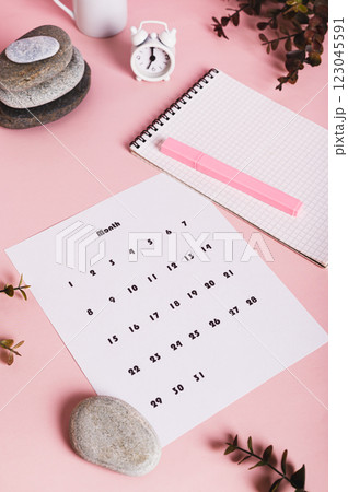 Calendar, alarm clock, notebook and pen on a pink background vertical view 123045591