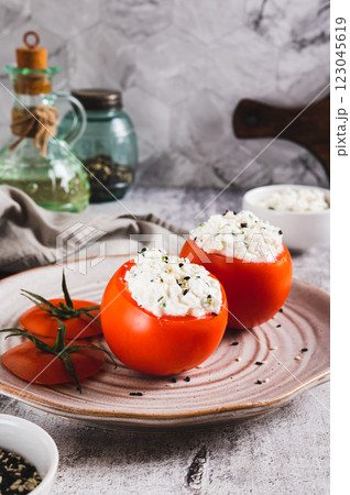 Fresh tomatoes filled with cottage cheese and herbs on a plate on the table vertical view 123045619