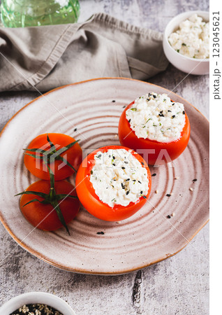 Tomatoes stuffed with cottage cheese and dill on a plate on the table vertical view 123045621