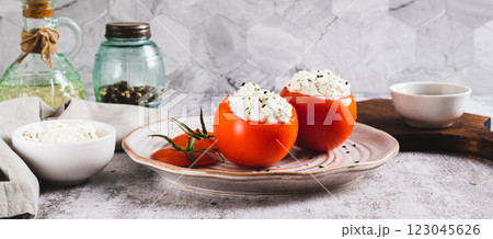 Fresh tomatoes filled with cottage cheese and herbs on a plate on the table web banner 123045626