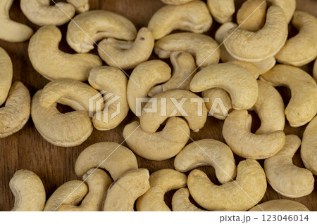 large cashew nuts are scattered on a larch board 123046014