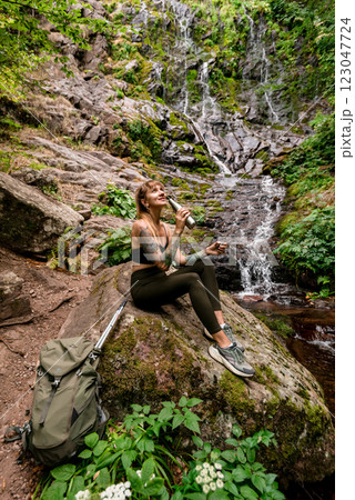 Woman Traveler Drinking Water near Mountain Waterfall Woman Traveler Drinking Water near Mountain Waterfall 123047724