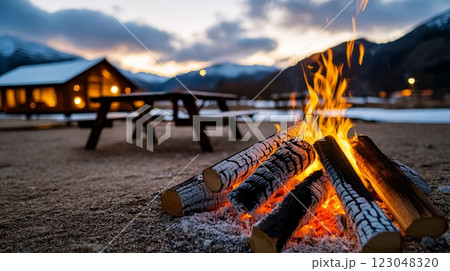 Cozy campfire by snowy mountain cabin at sunset. 123048320