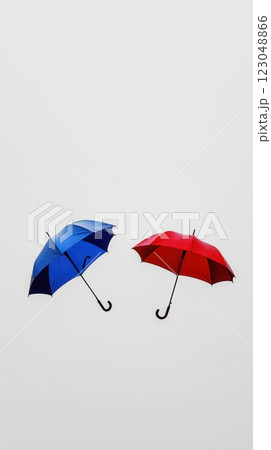 two wet open umbrellas in red and blue held upward against white background with raindrops copyspace concept of rain coverage insurance travel marketing 123048866