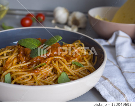 Balanesi pasta with basil leaves and tomato sauce served in a bowl, with ingredients like tomatoes, garlic, and cheese in the background, creating a delicious italian culinary scene 123049692
