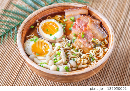 Hearty rustic ramen bowl with pork belly, beech mushrooms, and ramen eggs 123050091