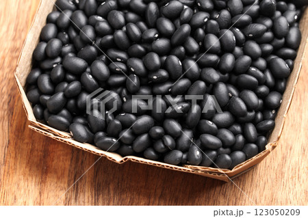 Organic black kidney beans in paper container on wooden table. Raw food packaging concept. Packing uncooked legumes 123050209