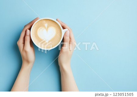 Woman holding cup of cappuccino with heart shape latte art on blue background Woman holding cup of cappuccino with heart shape latte art on blue background 123051505