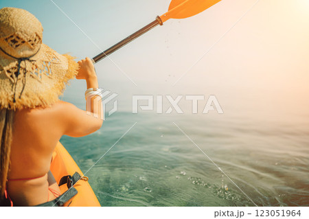 Woman in kayak back view. Happy woman with long hair in a swimsuit and hat floating in kayak on the sea. Summer holiday vacation. Summer holidays vacation at sea. Woman in kayak back view. Happy woman with long hair in a swimsuit and hat floating in kayak on the sea. Summer holiday vacation. Summer holidays vacation at sea. 123051964