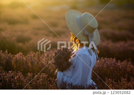 Lavender Field Woman Sunset: Woman harvests lavender at sunset in a picturesque field; summer, peaceful scene. Lavender Field Woman Sunset: Woman harvests lavender at sunset in a picturesque field; summer, peaceful scene. 123052082