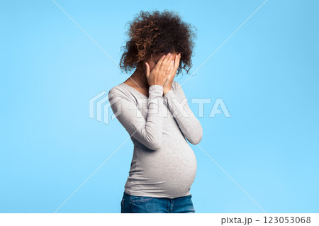 Depression during pregnancy. Afro woman covering face with hands and crying, grey background 123053068