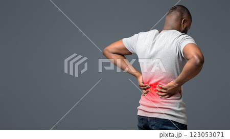 Afro guy holding both hands on lower back, pain in spine, inflamed zone highlighted in red, white background, free space 123053071