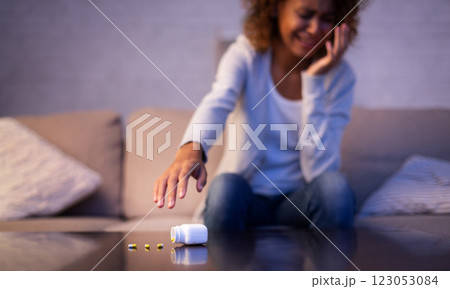 Depression. Crying afro woman taking antidepressant pills, sitting on sofa 123053084