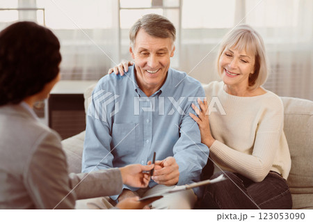 Happy senior couple about to sign document at meeting with financial advisor, female consultant giving pen to mature man 123053090