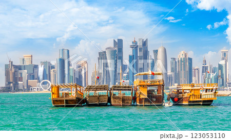 Traditional arab dhow fishermen boats with qatari flag at the sea bay with Doha futuristic business downtown center skyline, Qatar 123053110