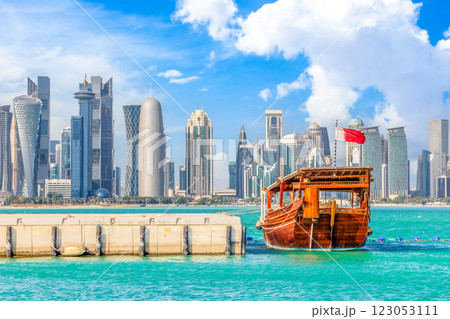 Traditional arab dhow fishermen boat with qatari flag at the sea bay with Doha futuristic business downtown center skyline, Qatar 123053111