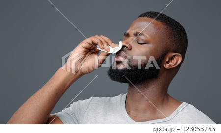Afro guy touching his nose with napkin, bleeding or having runny nose, free space 123053255