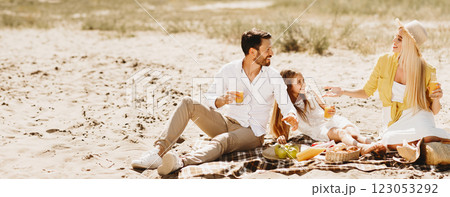 Family Having Summer Picnic Sitting On Blanket Talking And Eating Enjoying Sunny Day Outdoors In Countryside. Summertime Leisure And Vacation Family Having Summer Picnic Sitting On Blanket Talking And Eating Enjoying Sunny Day Outdoors In Countryside. Summertime Leisure And Vacation 123053292