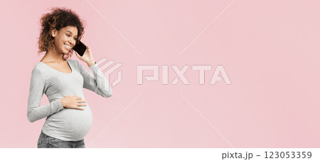 African-american expectant woman having phone conversation and touching belly over pink studio background African-american expectant woman having phone conversation and touching belly over pink studio background 123053359
